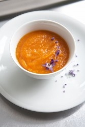 Karottensuppe mit Blüten angerichtet